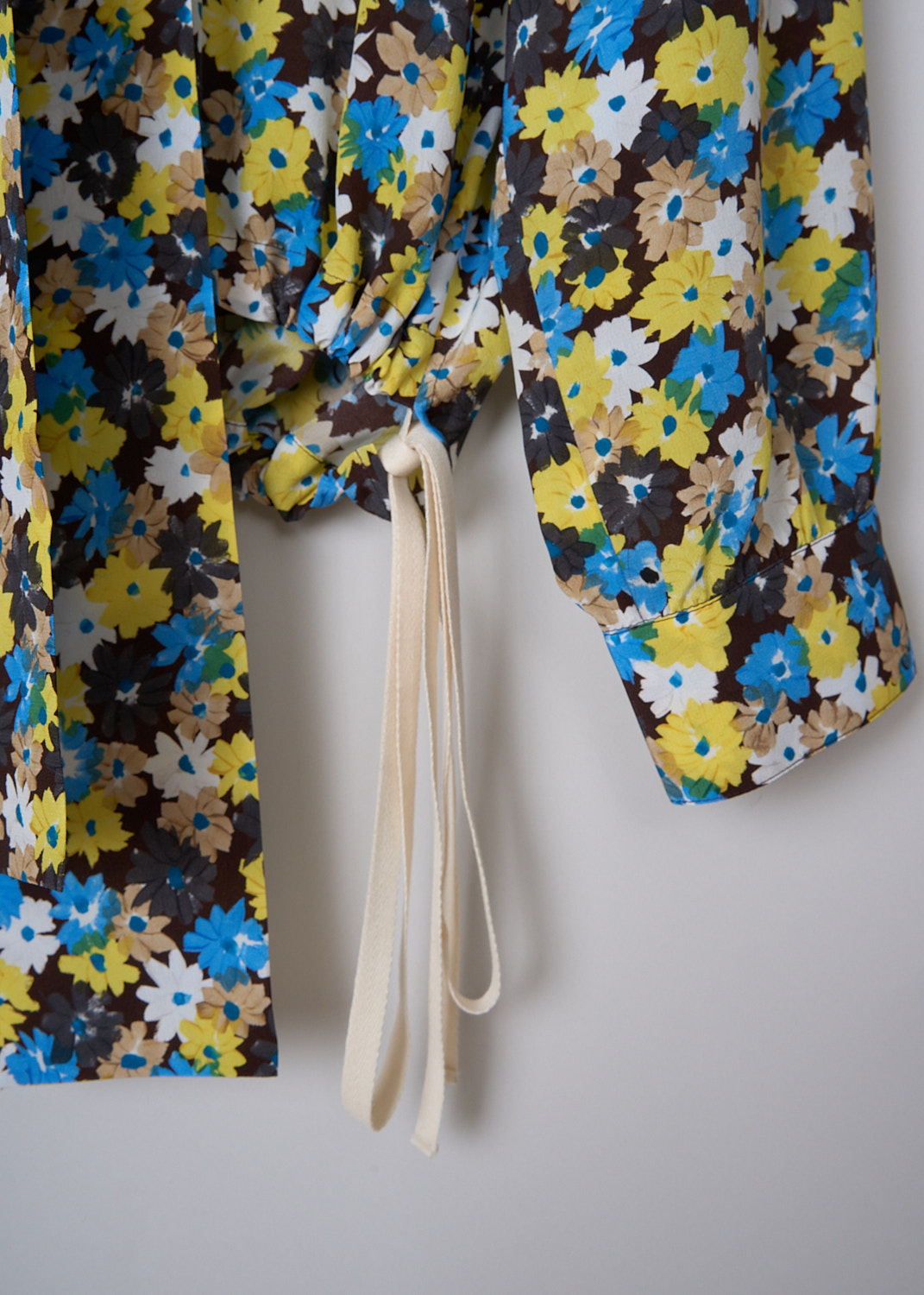 PLAN C, DAISY BOUQUET CRÊPE DE CHINE BLOUSE, CMCAD55K00_TS011_FIY04, Yellow, Print, Blue, Detail, This long sleeve Crêpe de Chine blouse has an all-over Daisy Bouquet print. The blouse has a bow-tie neckline. An inverted pleats runs vertically down the front. The long sleeves have buttoned cuffs. The blouse has a hemline with drawstrings on either side. In the back of the neck, the blouse has a concealed centre zip.


